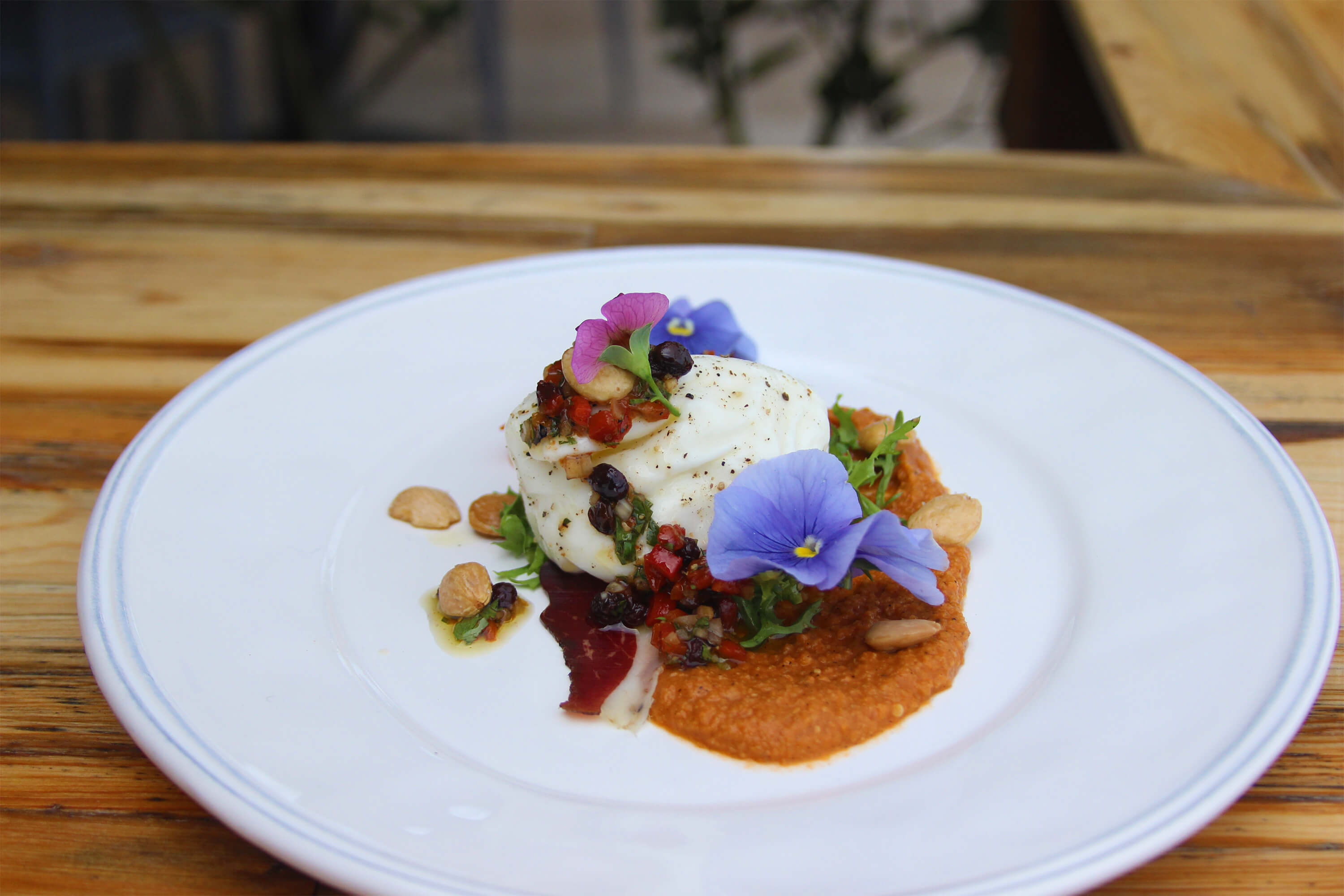 burrata plate with edible flowers from the garden and seasonal accompaniments