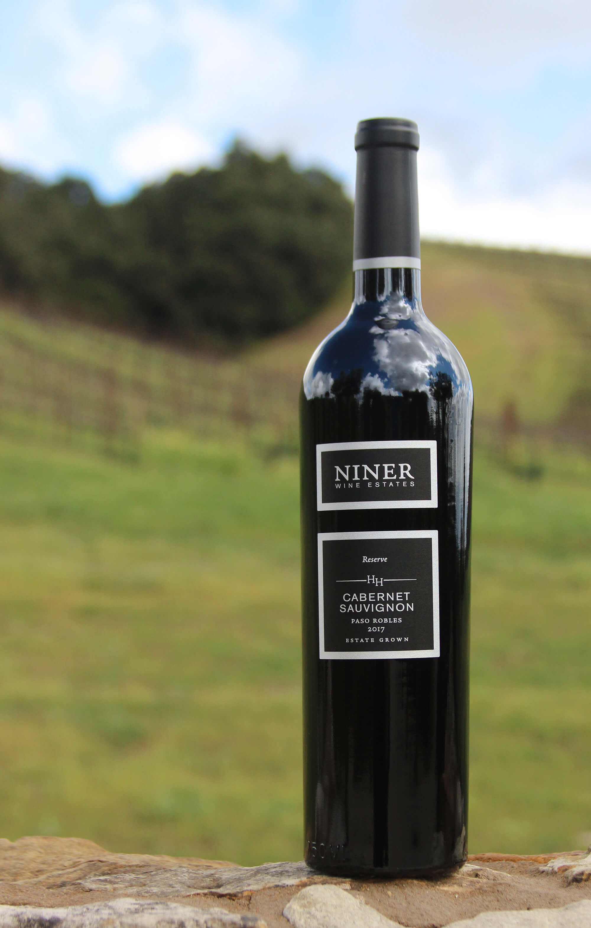 A bottle of Heart Hill Cabernet Sauvignon in front of Heart Hill Vineyard