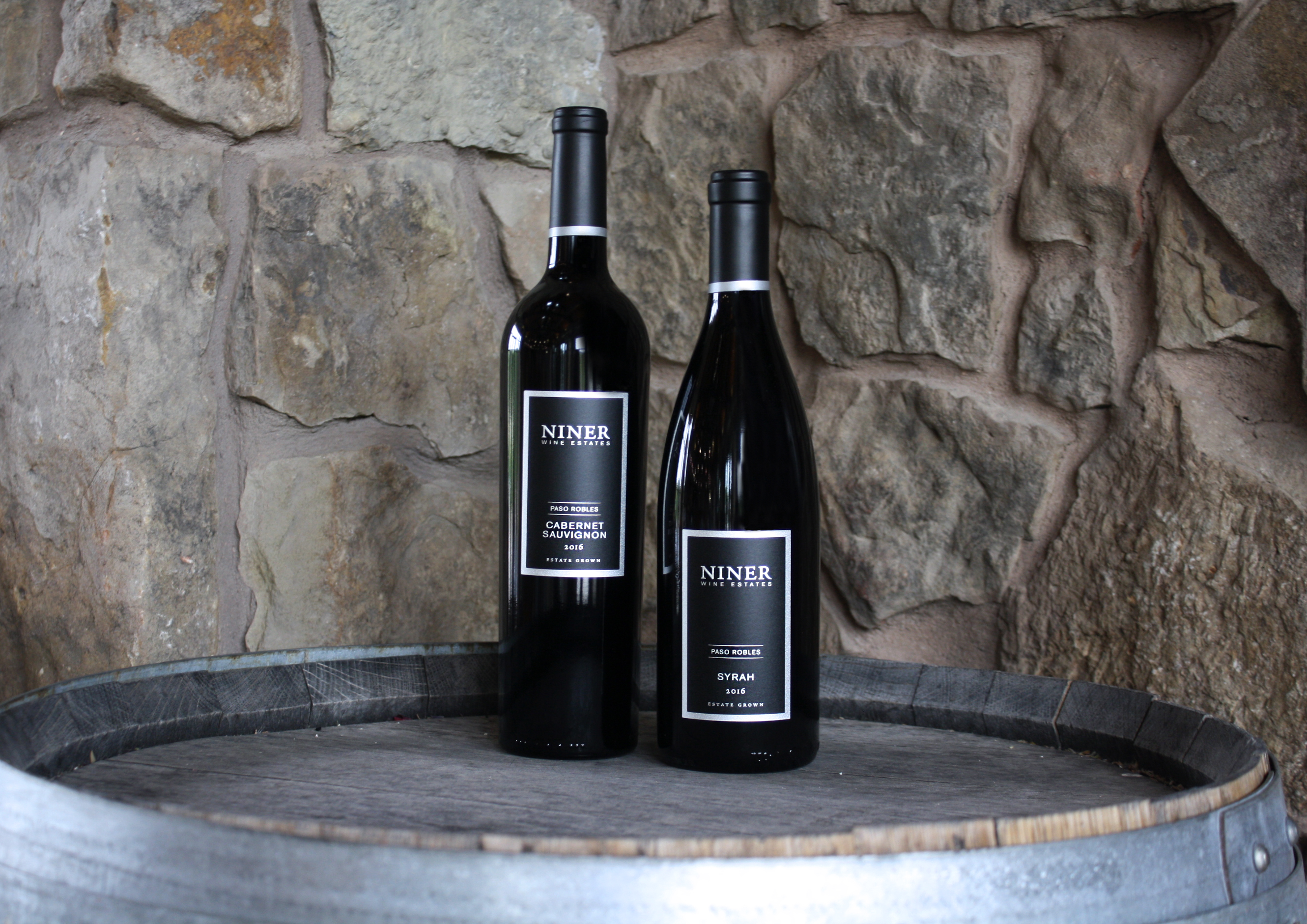 Bottles of Cabernet Sauvignon and Syrah on a barrel